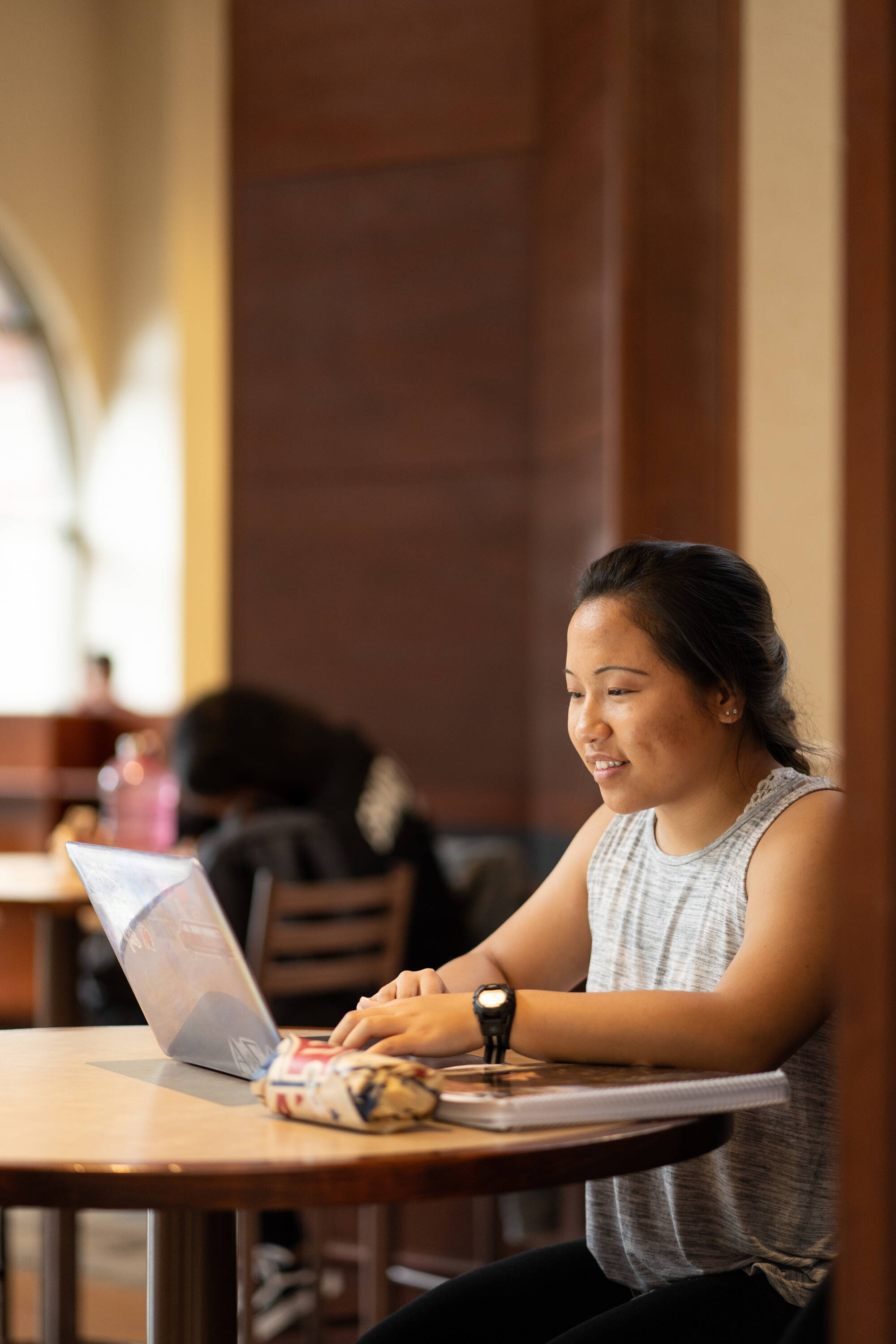woman sitting at table outside while working on laptop